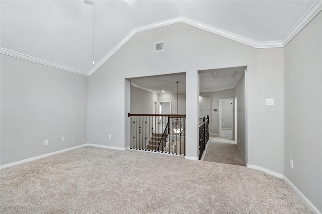 spare room featuring visible vents, ornamental molding, carpet flooring, attic access, and vaulted ceiling