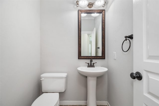 half bathroom featuring baseboards and toilet