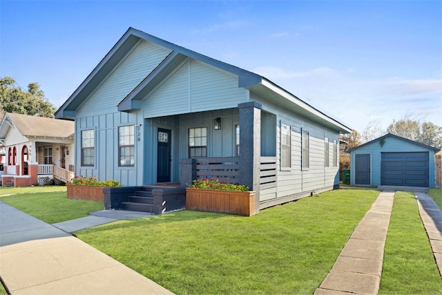 bungalow with a front lawn, a garage, and an outbuilding