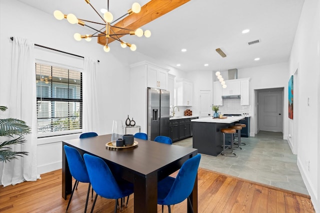 dining area featuring a notable chandelier, sink, and light hardwood / wood-style floors