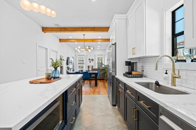 kitchen featuring white cabinetry, decorative light fixtures, sink, light stone counters, and appliances with stainless steel finishes