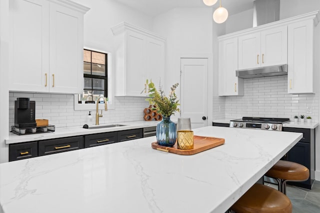 kitchen with sink, a kitchen breakfast bar, a kitchen island, white cabinets, and hanging light fixtures