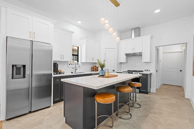 kitchen featuring hanging light fixtures, a center island, built in fridge, white cabinetry, and a kitchen bar