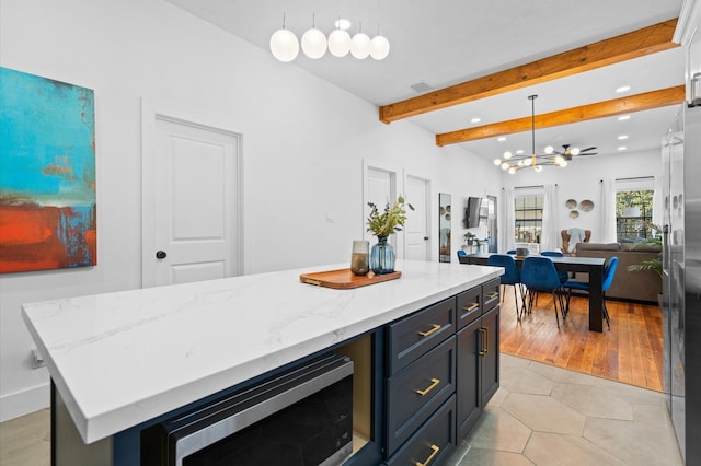 kitchen with light tile patterned floors, hanging light fixtures, stainless steel appliances, beamed ceiling, and a kitchen island