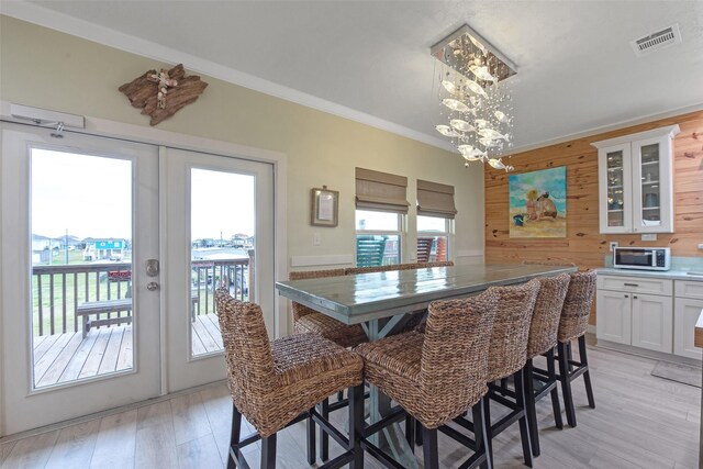 dining space with french doors, crown molding, a wealth of natural light, and wood walls