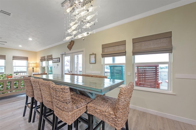 dining space with a notable chandelier, crown molding, french doors, and light wood-type flooring