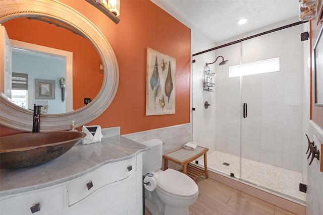 bathroom featuring toilet, a textured ceiling, vanity, a shower with door, and hardwood / wood-style floors