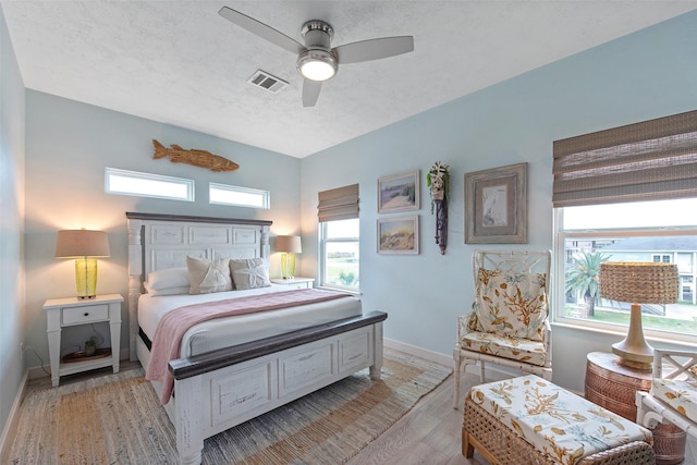 bedroom featuring light wood-type flooring, a textured ceiling, and ceiling fan