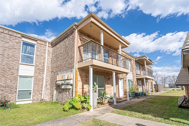 view of front of house with a balcony and a front yard