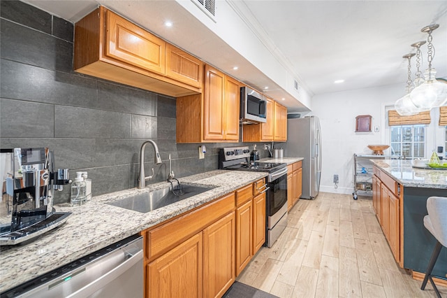 kitchen with sink, light wood-type flooring, stainless steel appliances, and light stone countertops