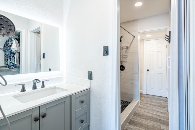 bathroom featuring vanity, wood-type flooring, and tiled shower