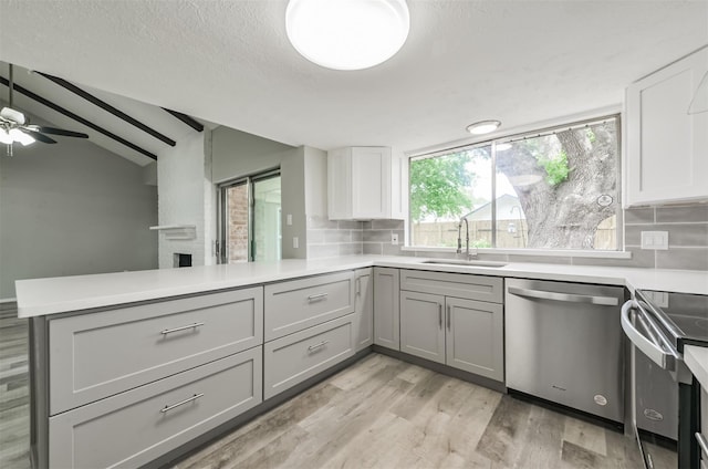 kitchen featuring sink, tasteful backsplash, vaulted ceiling, appliances with stainless steel finishes, and kitchen peninsula