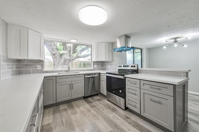 kitchen with sink, stainless steel appliances, tasteful backsplash, island range hood, and kitchen peninsula