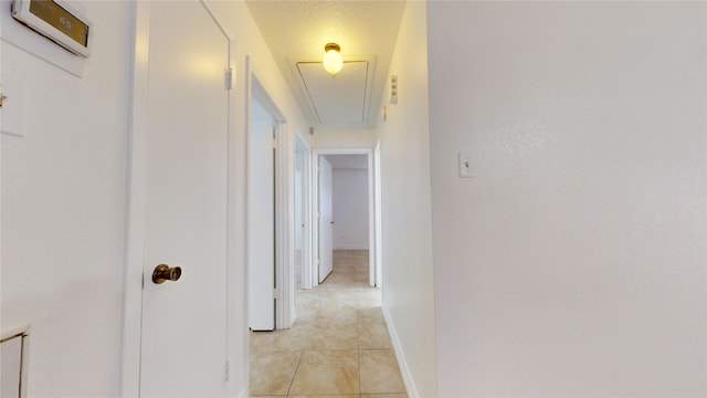 corridor with light tile patterned flooring and a textured ceiling