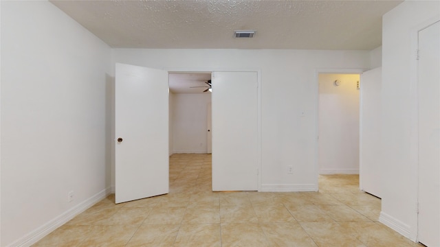 tiled empty room with a textured ceiling and ceiling fan