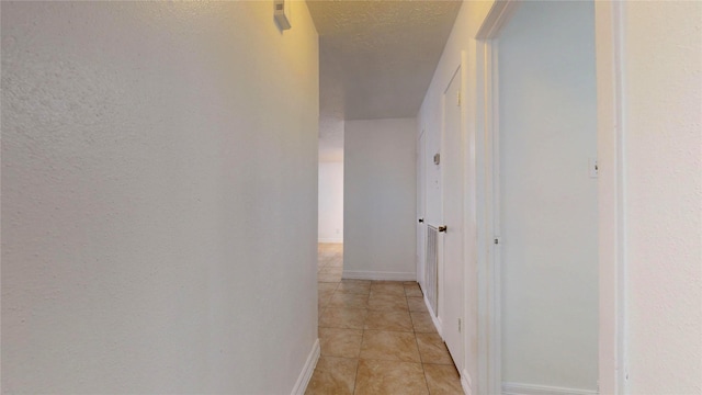 hallway featuring light tile patterned floors and a textured ceiling