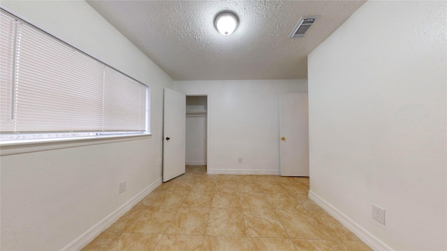 unfurnished bedroom featuring light tile patterned floors, a textured ceiling, and a closet