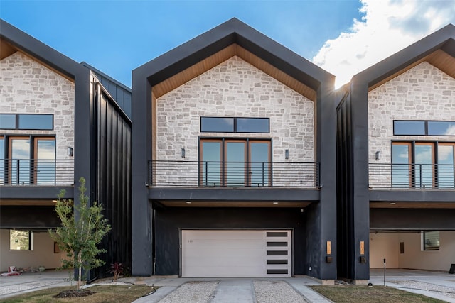 view of front of home with a garage, stone siding, and stucco siding