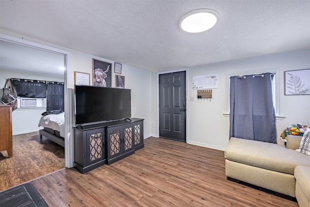 living room featuring cooling unit, hardwood / wood-style flooring, and a textured ceiling