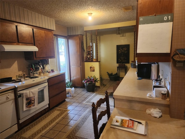 kitchen with white appliances, a textured ceiling, and light tile patterned floors