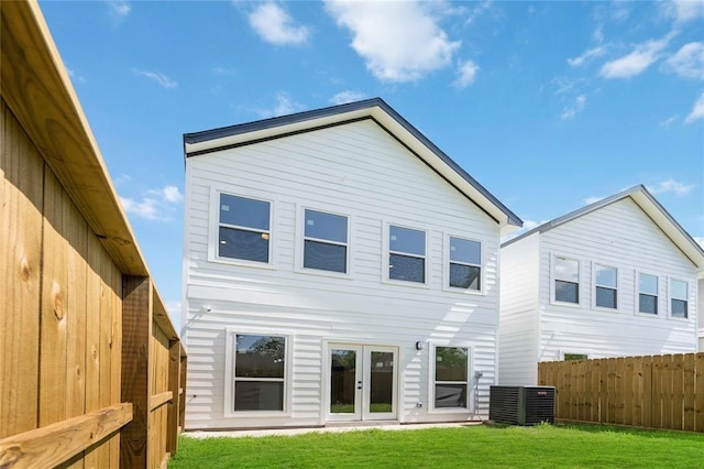 rear view of property featuring french doors, a lawn, and central air condition unit