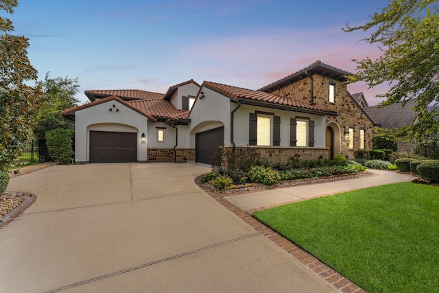 mediterranean / spanish home featuring a garage, stone siding, concrete driveway, a tiled roof, and stucco siding