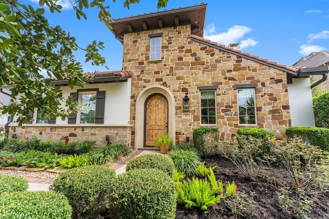 mediterranean / spanish-style house featuring stone siding and stucco siding