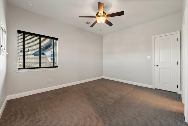 spare room featuring ceiling fan, dark carpet, visible vents, and baseboards