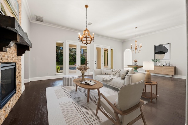 living area featuring an inviting chandelier, visible vents, dark wood finished floors, and a glass covered fireplace