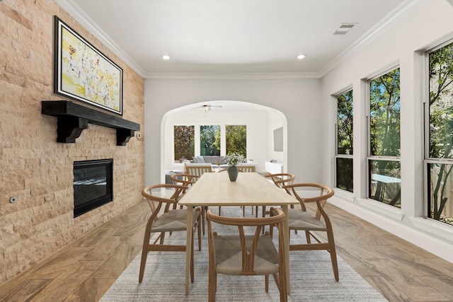 dining area with arched walkways, recessed lighting, a fireplace, visible vents, and crown molding