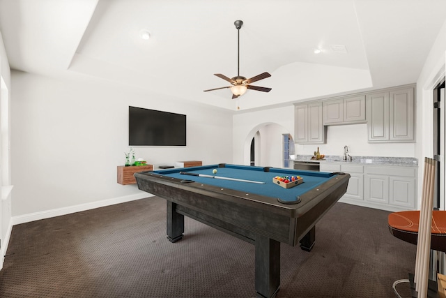 game room featuring arched walkways, dark colored carpet, a sink, and a raised ceiling