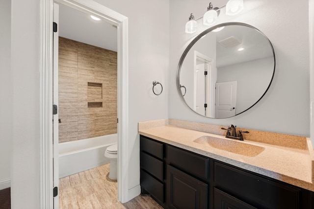 bathroom with bathtub / shower combination, toilet, wood finished floors, visible vents, and vanity