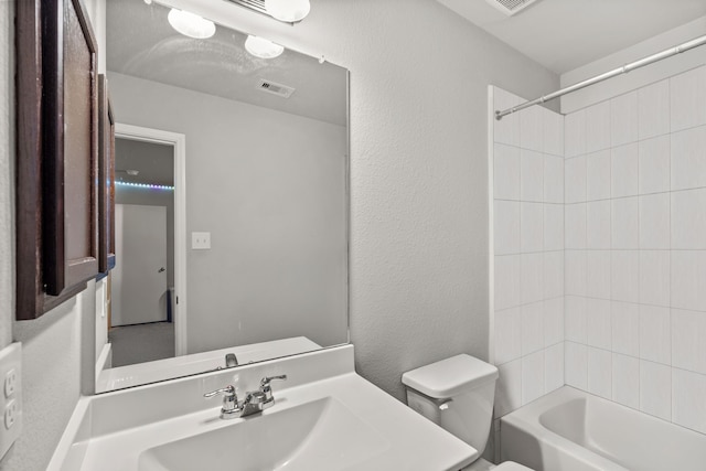 full bathroom featuring tiled shower / bath combo, vanity, and toilet