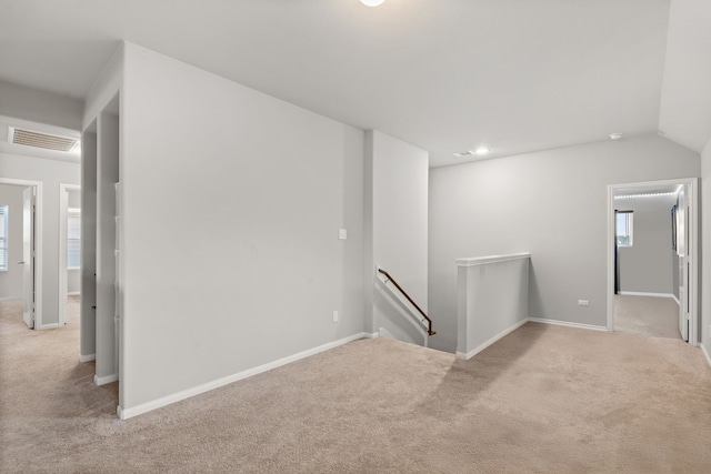 spare room with light colored carpet and lofted ceiling