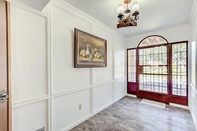 foyer entrance featuring a notable chandelier and crown molding