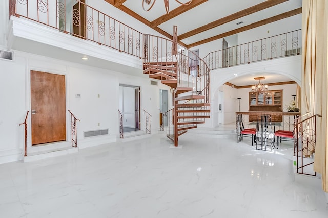 staircase featuring a high ceiling, an inviting chandelier, and beam ceiling