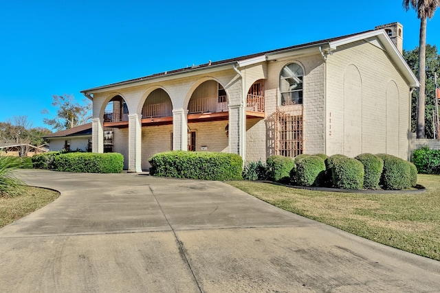 view of front of house featuring a balcony and a front yard