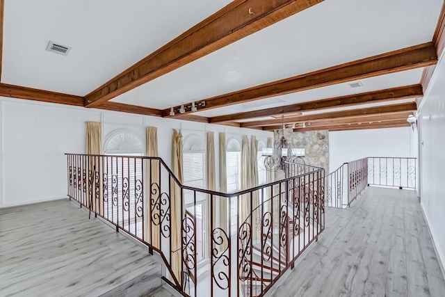 corridor featuring a notable chandelier, light hardwood / wood-style floors, and beamed ceiling