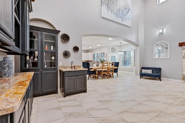 kitchen featuring a high ceiling, sink, and light stone counters