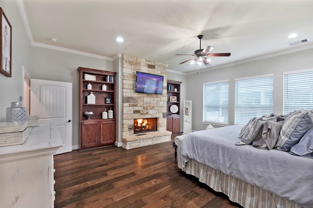 bedroom featuring a stone fireplace, ornamental molding, dark hardwood / wood-style floors, and ceiling fan