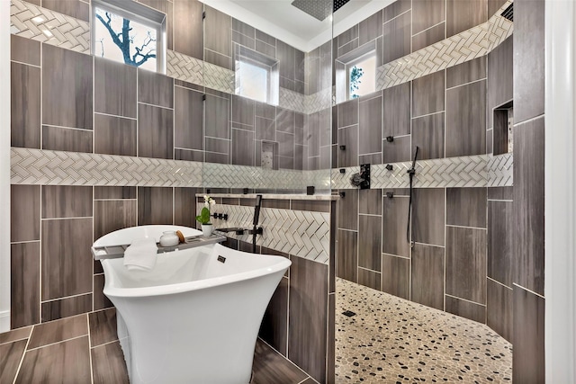 bathroom featuring shower with separate bathtub and tile walls