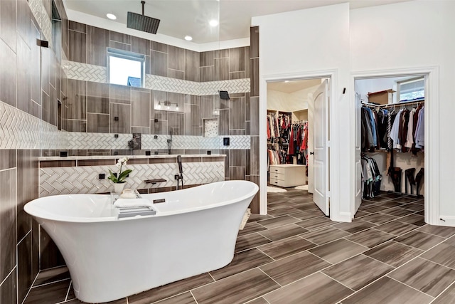 bathroom with shower with separate bathtub and tile walls