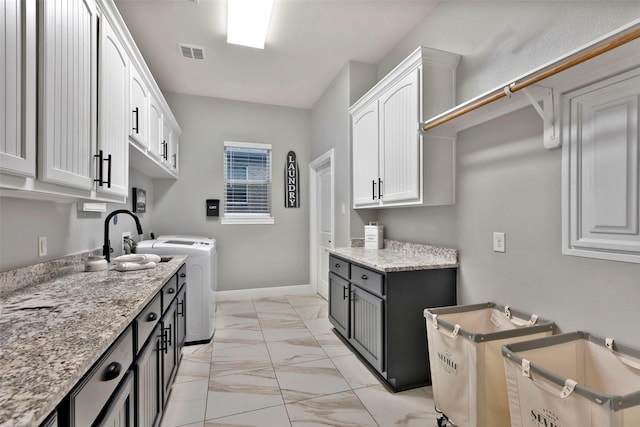 kitchen featuring white cabinetry, light stone countertops, and washing machine and dryer