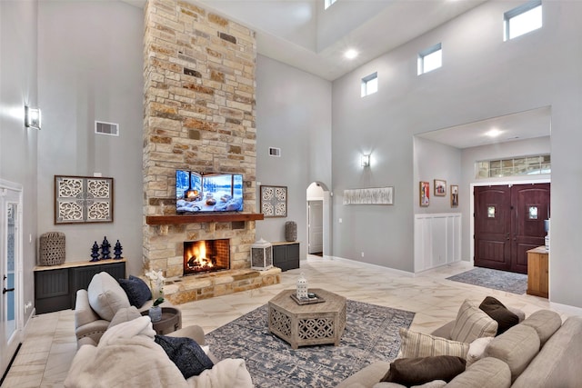 living room with a stone fireplace and a towering ceiling