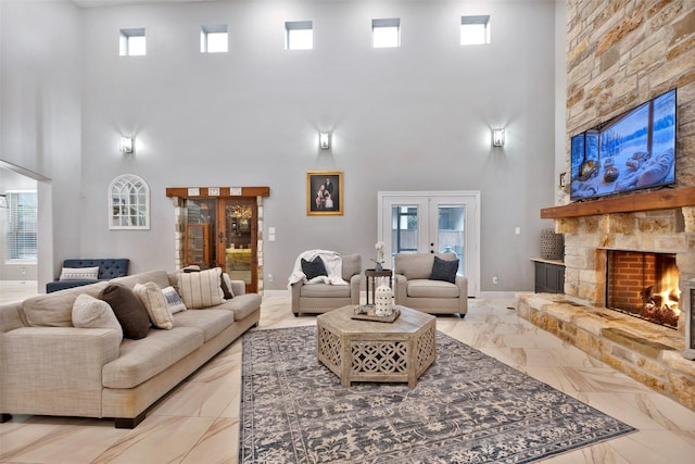 living room featuring a stone fireplace, french doors, a healthy amount of sunlight, and a towering ceiling