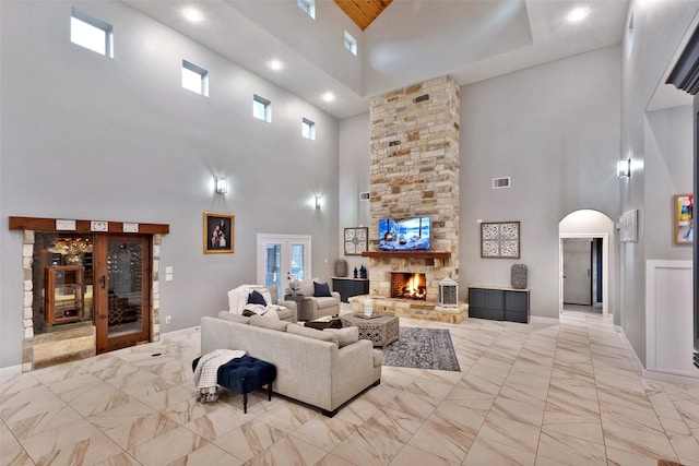 living room with a stone fireplace and a high ceiling