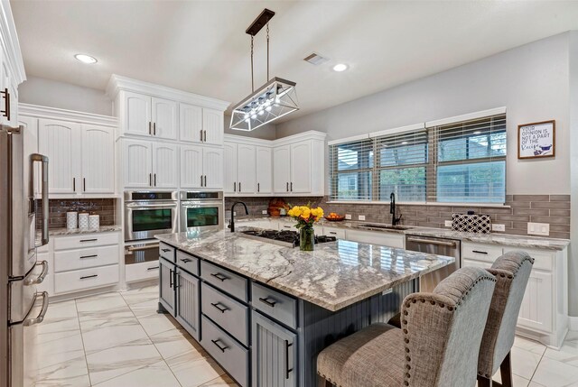 kitchen featuring appliances with stainless steel finishes, white cabinetry, sink, gray cabinetry, and a center island