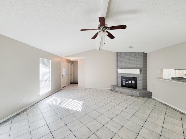 unfurnished living room featuring light tile patterned flooring, lofted ceiling with beams, ceiling fan, a brick fireplace, and a textured ceiling