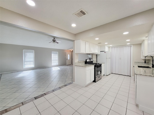 kitchen with white cabinetry, sink, light tile patterned floors, and stainless steel gas range