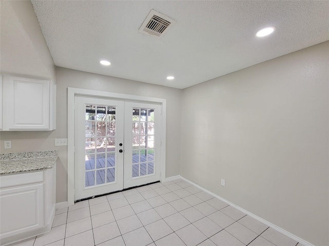 doorway to outside with french doors, a textured ceiling, and light tile patterned floors